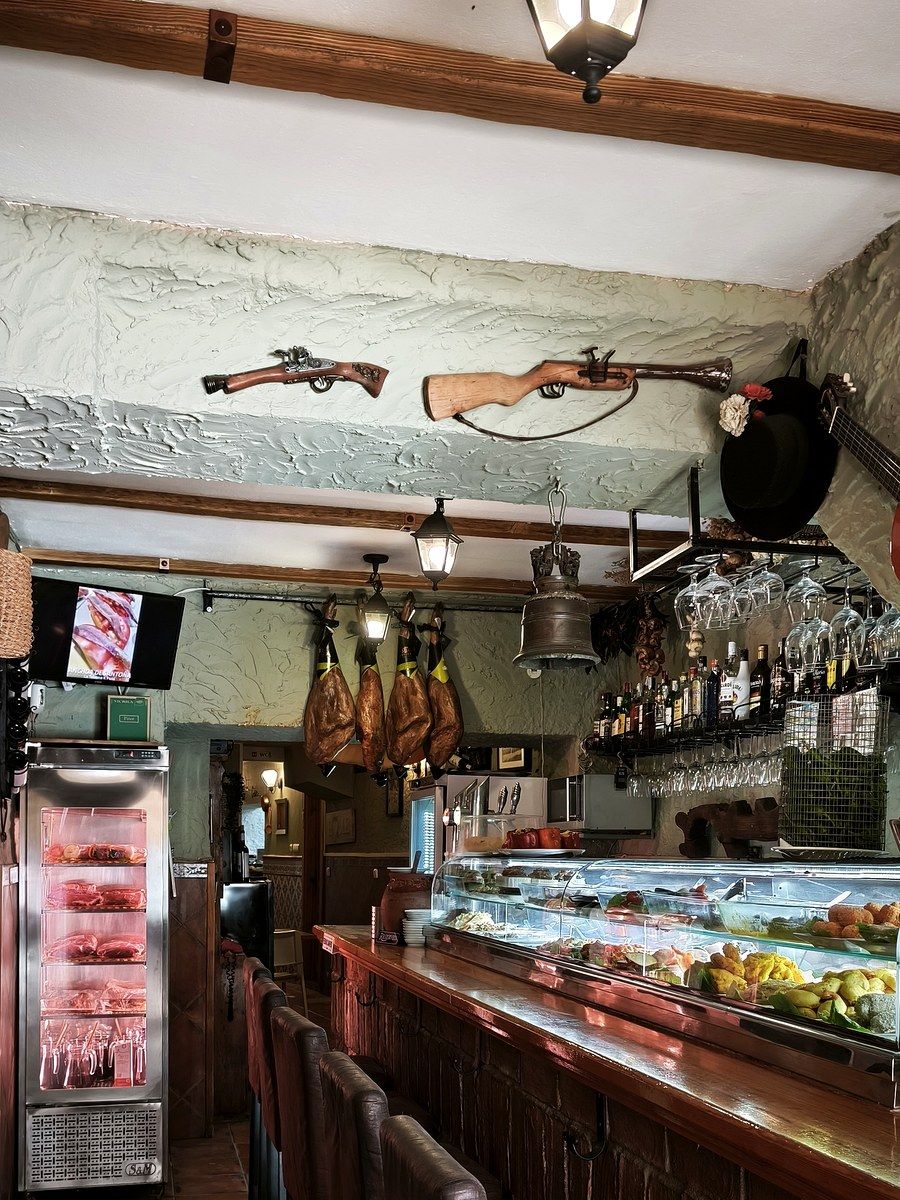 La barra de Taberna K Pasa, con jamones colgados y la decoración del local